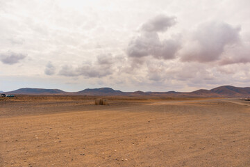 Fototapeta na wymiar Desert landscape of white sand with big white clouds in the sky. Fuerteventura, Canary Islands, Spain