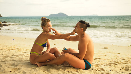 Cute loving couple each other having sun block. Woman to put sunscreen man. Young girl and guy face to face using sun cream. Concept rest tropical resort, traveling tourism happy summer holidays