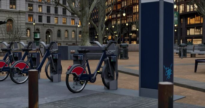 Row of Green bicycles for rent. Electric bicycle charging station. Shared electric bikes parked on city street early in the morning