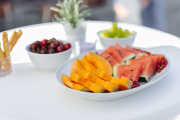 Fresh-cut fruits in bowls on a white tablecloth at a summer wedding