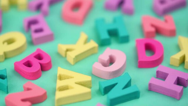 closeup wooden colorful letters of the ABC alphabet rotate on a turquoise background. back to school. concept of learning and gaining knowledge. latin alphabet. macro.