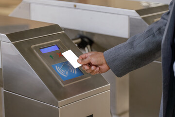 Detail of a man's hand paying with blank contactless card for a subway ticket.