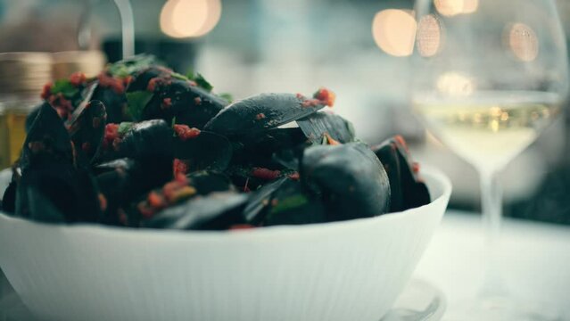Hot black mussels with vegetable sause and a glass of white wine. Mediterranean sea cuisine