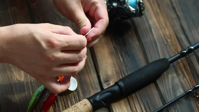 A man is tying a fishing knot on a fishing bait, preparation for fishing, jig fishing, horizontal video