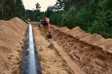 Natural gas pipeline construction. Excavator dig trench at forest. Backgoe on earthwork for laying...