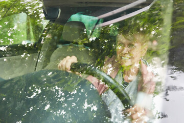 Happy elderly woman driving car during road trip