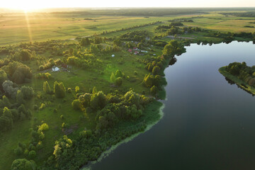 Lake in rural on sunset, drone view. Rural landscape with lakes. Drink water safe. Global drought crisis. Pond in countryside with fields. Green farm field and farmland in Country. Village at lake.