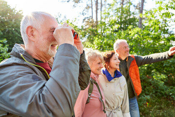 Smiling elderly couples bird watching in forest during vacation