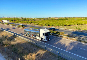 Isothermal Tank truck driving on highway. Oil and Gas Transportation and Logistics. Metal chrome cistern tanker with petrochemicals. Liquid Chemical Freight and foodstuff.