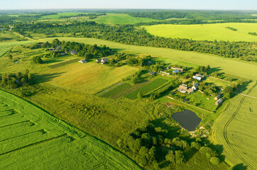 Obraz premium Rural landscape. Country houses in countryside. Village Home in Country. Wooden house in Russian village. Agricultural field with Suburban house. Rural building in countryside. Green field background