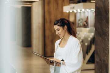 Happy brunette female interior designer choosing flooring tile color texture samples at store shop....