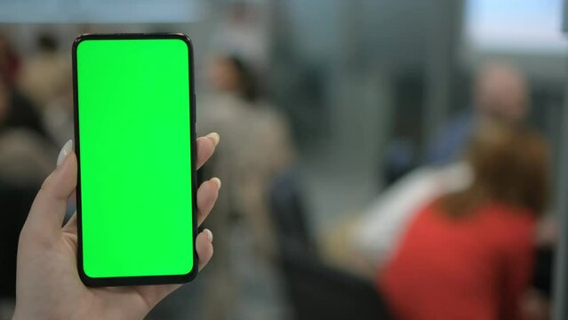 A woman with a smartphone in her hand. Point of View of Woman at Phone with Green Screen for Copy Space. The concept of a successful business woman, feminism. Close-up.