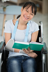 woman reading book in a wheelchair with arm in sling
