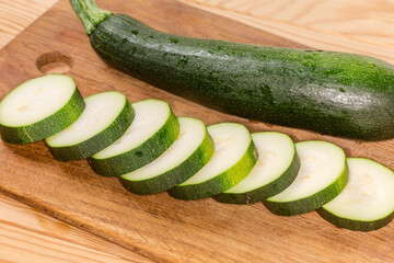 Sliced dark green zucchini against Whole zucchini on cutting board