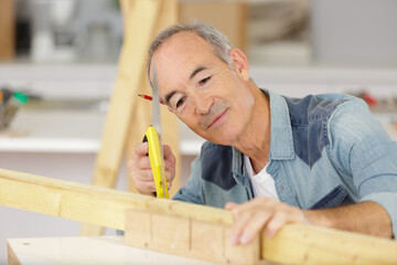 senior man cutting wood at home