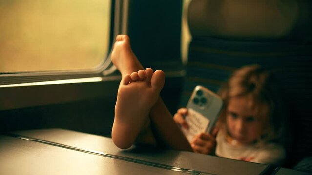 Little girl uses her smartphone whle traveling in the high-speed train