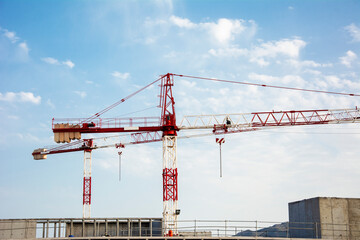 Building under construction with large tonnage cranes with the blue sky background