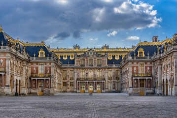 Facade of the baroque style Versailles Palace in France during a cloudy evening. 