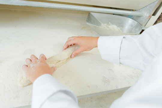 Hands shaping dough into baguette shape