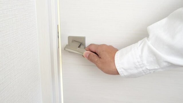 ドアノブに触れて静電気に驚く男性