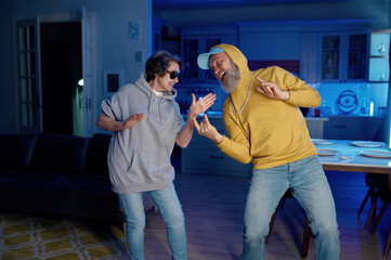 Two old people dancing at home kitchen having good time together