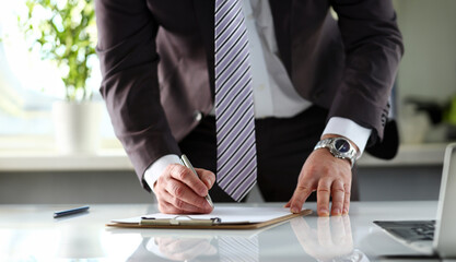 Male arm in suit and tie fill form clipped to pad with silver pen closeup. Sign gesture read pact...