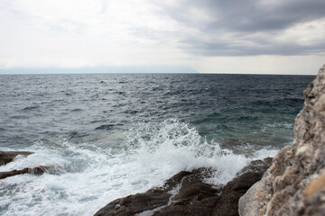 Fototapeta na wymiar Panorama of beautiful white sea waves and white stones. Cloudy summer time.