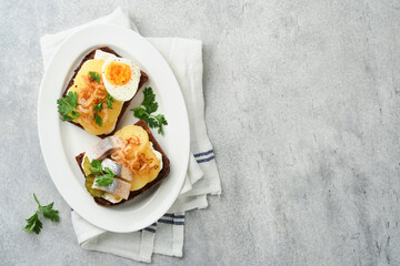 Open sandwich or smorrebrod with rye bread, herring, eggs, caramelized onions, parsley and cottage cheese on old wooden rustic table backgrounds. Danish or Scandinavian traditional food snack lunch.