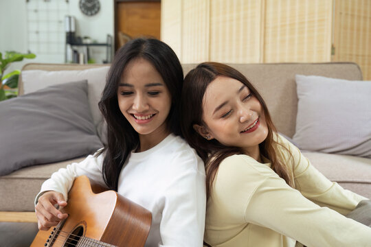 LGBTQIA lesbian gay couple playing guitar and singing with romantic feelings at home