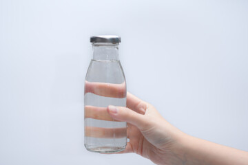 Izolowana szklana butelka z wodą do picia w dłoni  - obrazy, fototapety, plakaty