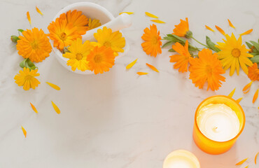 orange marigold  flowers with burning candles   on white marble background