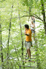 adults crossing rope bridge suspended between trees