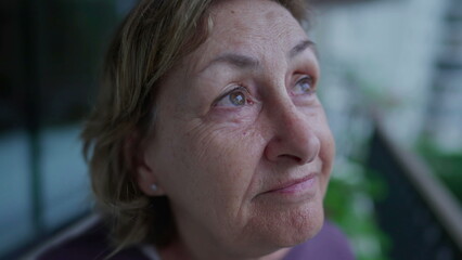 Close-up face of a senior woman staring at sky in contemplation. Pensive older lady in 70s with thoughtful expression