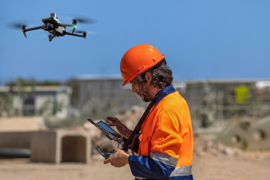 drone operator with remote control for a thermal UAV camera, surveying a construction site, in an industrial area