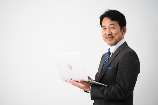 笑顔でノートパソコンを操作するミドル男性　ビジネスイメージ