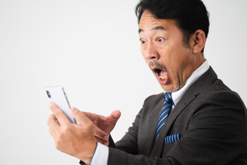 スマートフォンを持って驚いているミドル男性　ビジネスイメージ