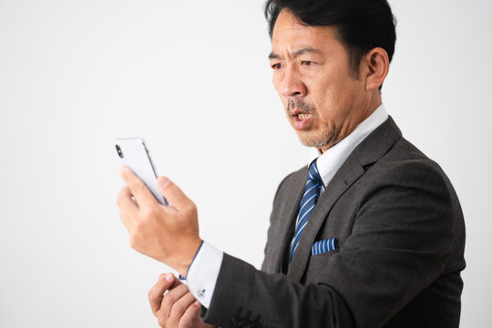 スマートフォンを持って驚いているミドル男性　ビジネスイメージ