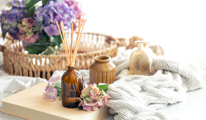 Naklejka na ściany i meble Aroma diffuser with the stick perfume, knitted element and flowers.