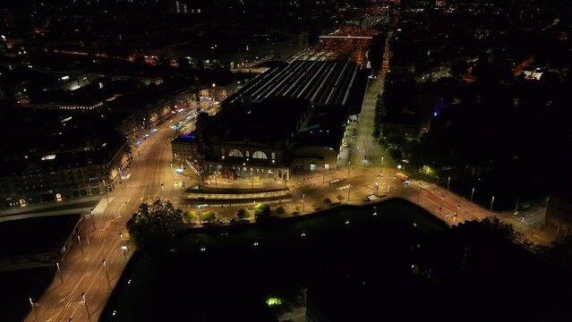 High angle view of historic building of Hauptbahnhof and glowing streets around. Tilt up reveal night city scenery. Zurich, Switzerland