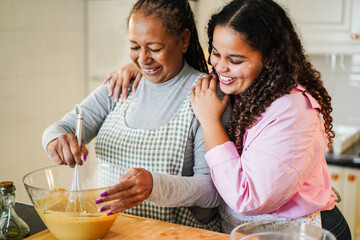 African mother and daughter having fun preparing free sugar cake at home - Family lifestyle and...