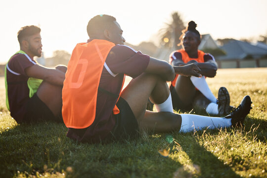Rugby, team and men relax on field outdoor, talking and communication at sunrise in the morning. Sports, athlete group and players sitting on grass after exercise, training or friends workout in game