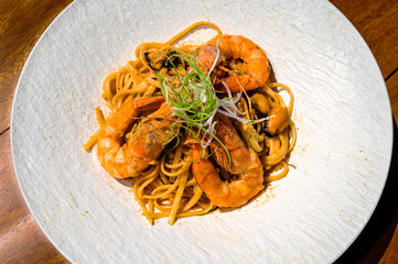 Succulent tiger shrimps and plump mussels gracefully adorning a mound of perfectly cooked spaghetti, presented on a clean white plate. Close-up photo. Selective focus.