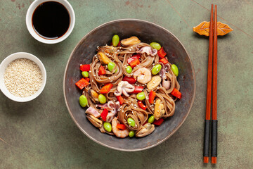Japanese soba noodles with vegetables, edamame beans and seafood. Asian cuisine. Top view