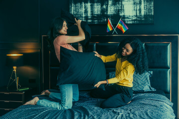 Lesbian partners' indoor pillow fight strengthens romance, and fills the room with affectionate.