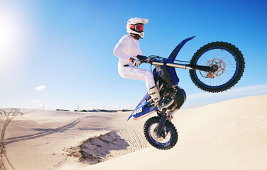 Jump, sports and man on motorcycle on sand for adrenaline, adventure and freedom in desert. Action, extreme motorbike and male person on bike on dunes for training, exercise and race or challenge