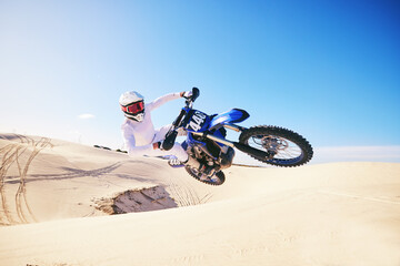 Sand, motor sports and man in air with motorbike for adrenaline, adventure and freedom in desert. Action, extreme sport and male person on bike on dunes for training, exercise and race or challenge - obrazy, fototapety, plakaty