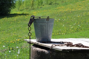 Water bucket attached to an old well, drinkable water accessibility