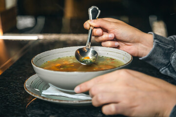 A woman in a cafe eats a low-calorie vegetable soup.