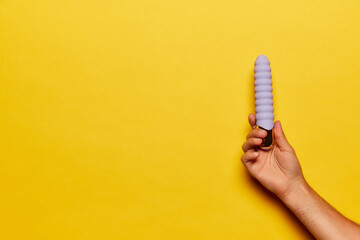 Female hand with vibrator, medical massager over bright yellow background. Image for sex shop....