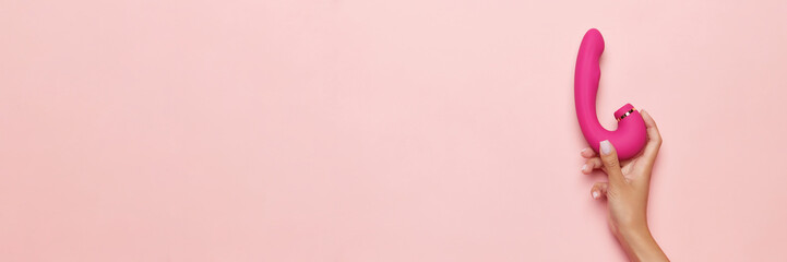 Banner. Female hand with vibrator, medical massager over pastel pink background. Image for sex shop. Concept of woman health, medicine, ad - obrazy, fototapety, plakaty